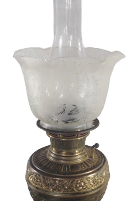 Antique Bradley & Hubbard Piano Oil Lamp, from the 1888s. The lamp features a brass base with intricate detailing, a slender stem, and a glass shade with etched patterns. The lamp showcasing the craftsmanship of the Victorian era.